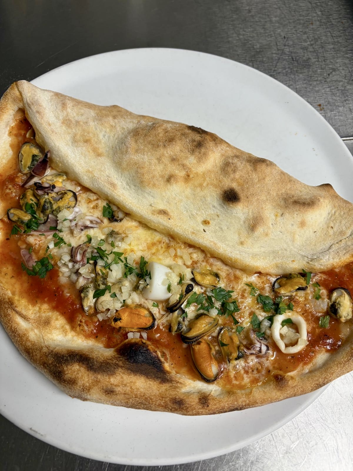 Pizza mit Meeresfrüchten und teilweise gefaltetem Teig